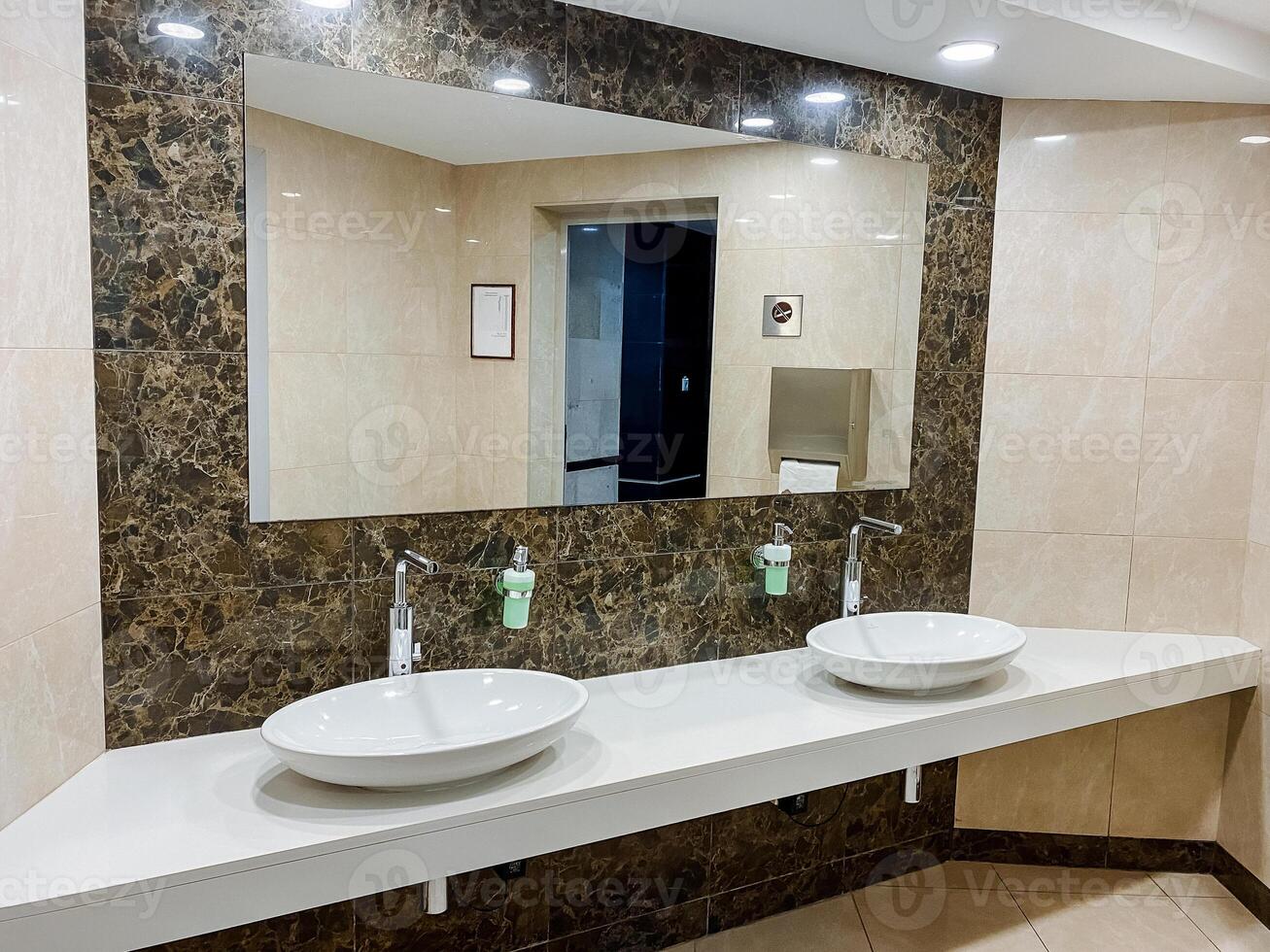 A contemporary bathroom featuring double sinks and a spacious mirror for a stylish interior design. photo