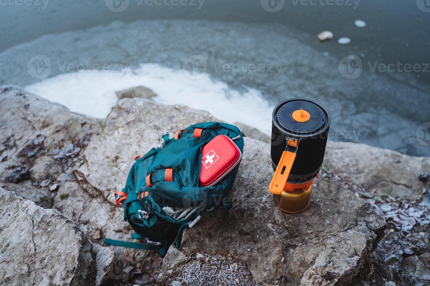 A set of camping equipment, equipment for hiking in the forest, a red box, a first aid kit is in the pocket of the backpack, a gas burner, a cooking system. photo