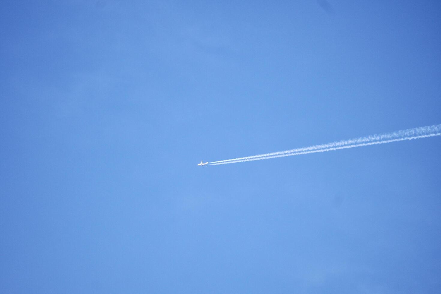 Fast airplane with white smoke lines isolated on horizontal clear blue sky outdoor environment background. photo