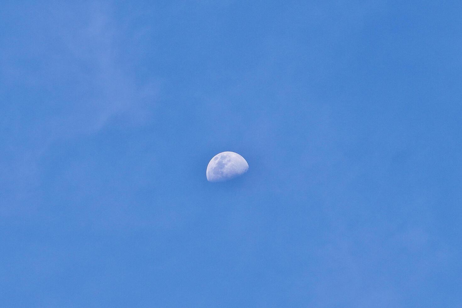 Beautiful half white moon visible on sunny daytime blue sky isolated on horizontal outdoor environment background. photo