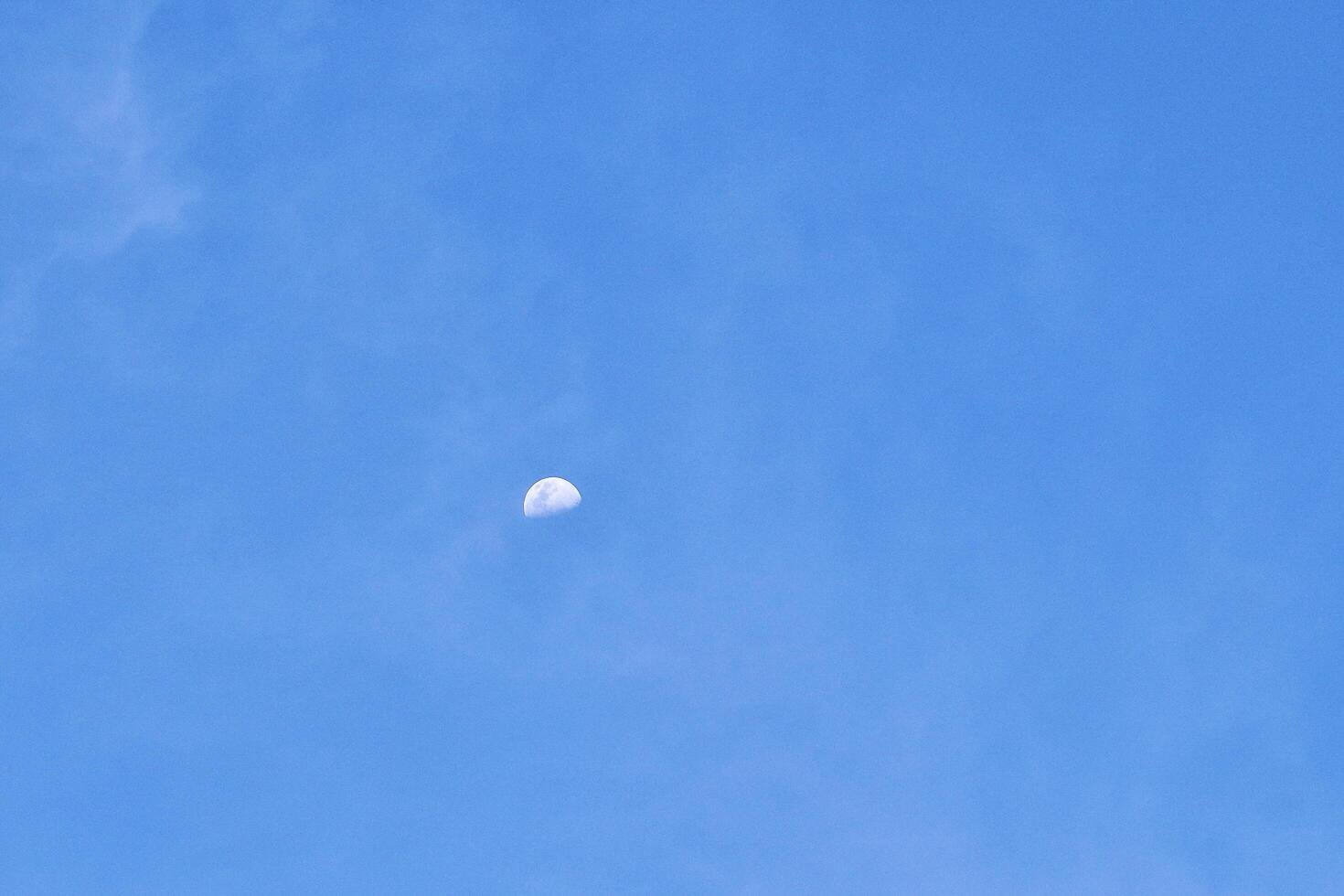 Half white moon visible on sunny daytime blue sky isolated on horizontal copy spaced outdoor environment background. photo