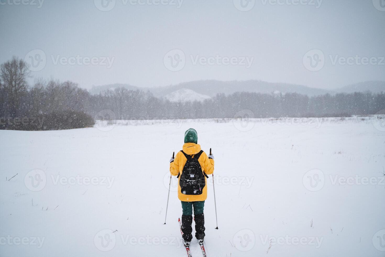 A person wearing a bright yellow jacket is joyfully skiing down a snowy slope, enjoying the winter weather and the exciting outdoor recreation that comes with this beautiful season photo