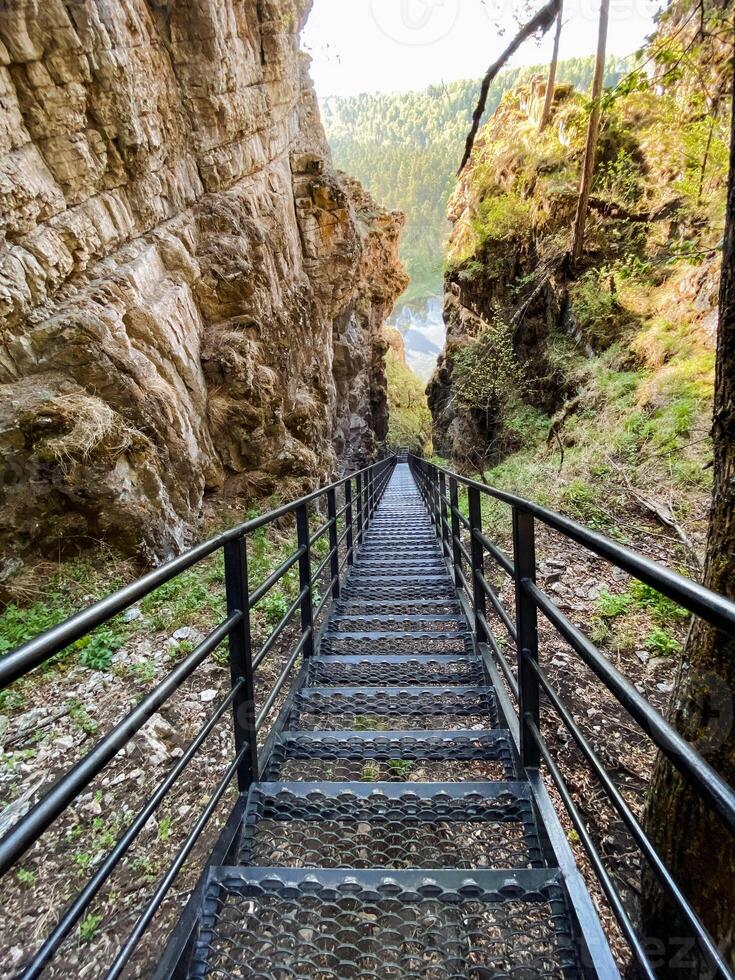 There is a beautifully constructed set of stairs that ascends gracefully up to a high cliff situated in the breathtaking depths of a canyon, creating a stunning view of the landscape photo