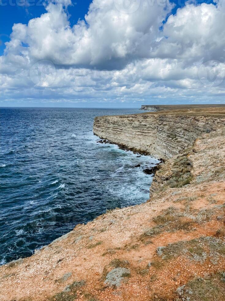 A stunning, towering cliff majestically looms over the vast ocean on a moody, overcast day, creating a breathtakingly beautiful view that captivates all who gaze upon it with wonder photo