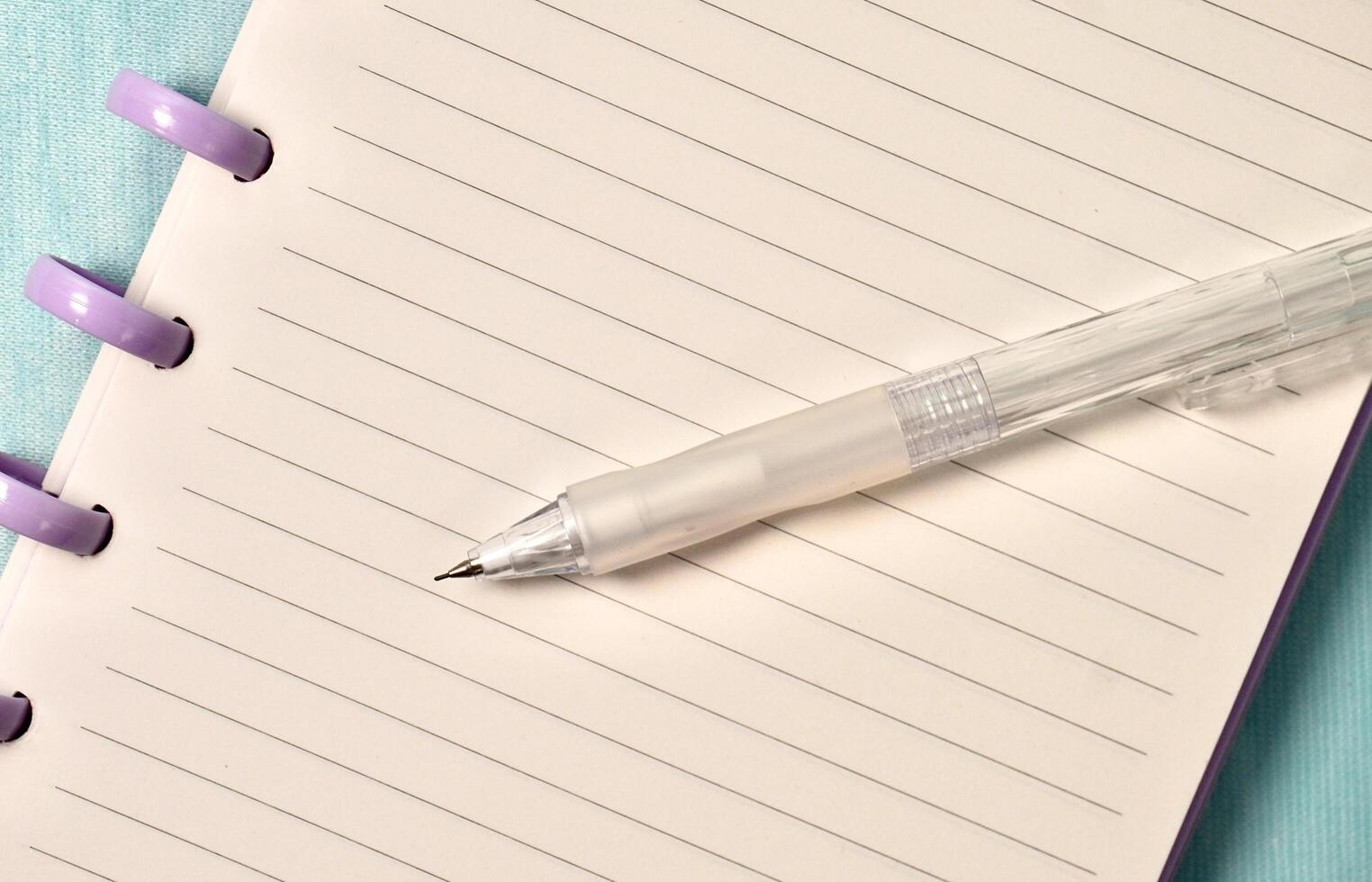 Close up cropped note book with white lined paper and mechanical pencil isolated on horizontal light blue background. photo