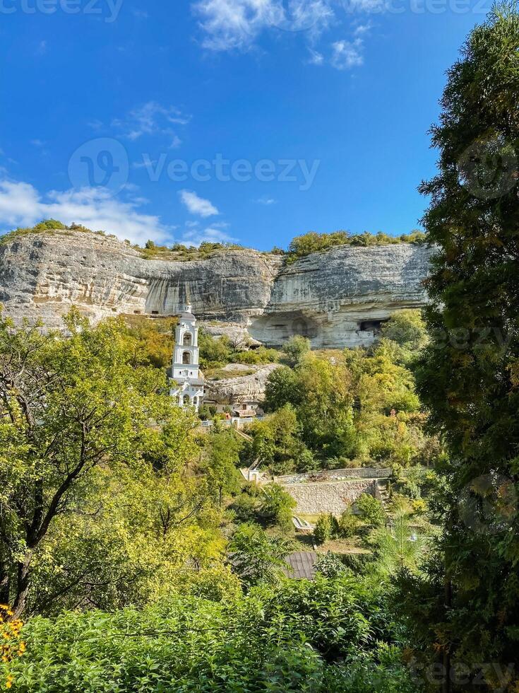 A beautiful church is situated on the top of a scenic hill, which is entirely surrounded by lush trees, creating a serene and tranquil environment that invites reflection and peace photo