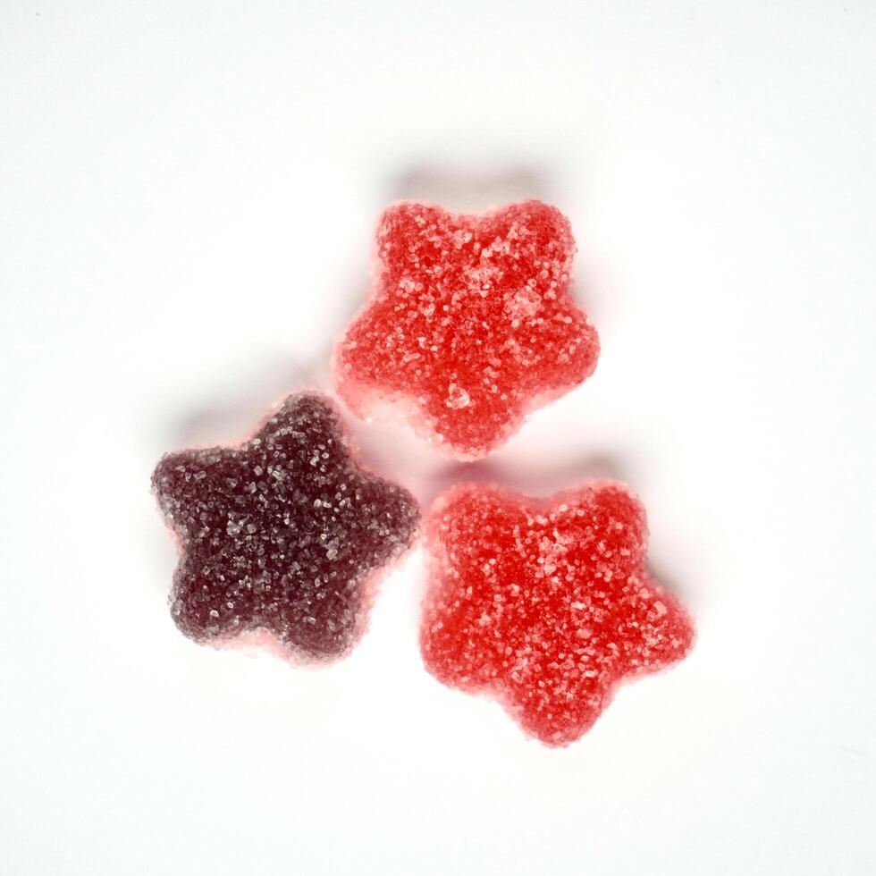 Three pieces of sugar coated star shaped chewy gummy candy isolated on square white background from top angle view. photo