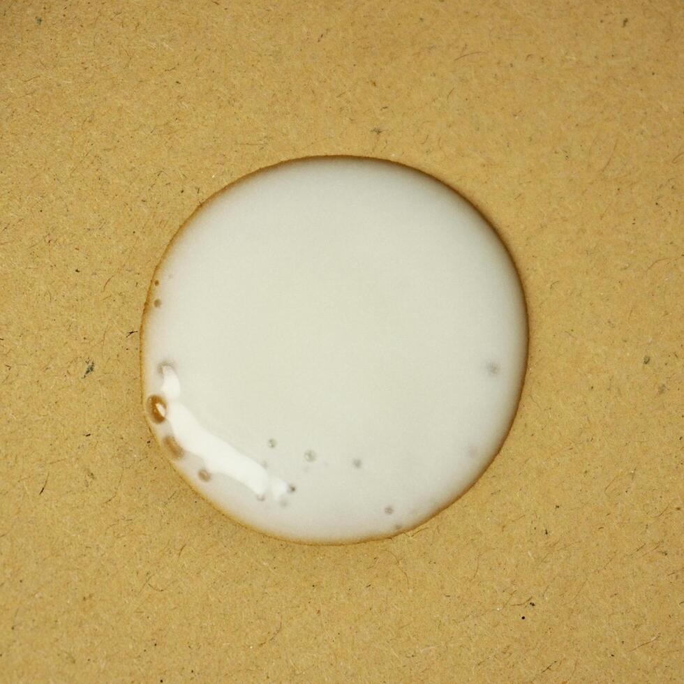 Acne cream gel drop texture isolated on square brown paper background. photo