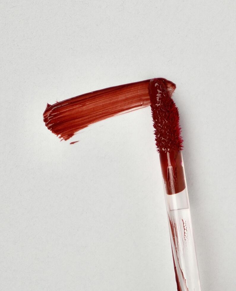 One piece of red brown lip cream brush applicator isolated on vertical white background. photo