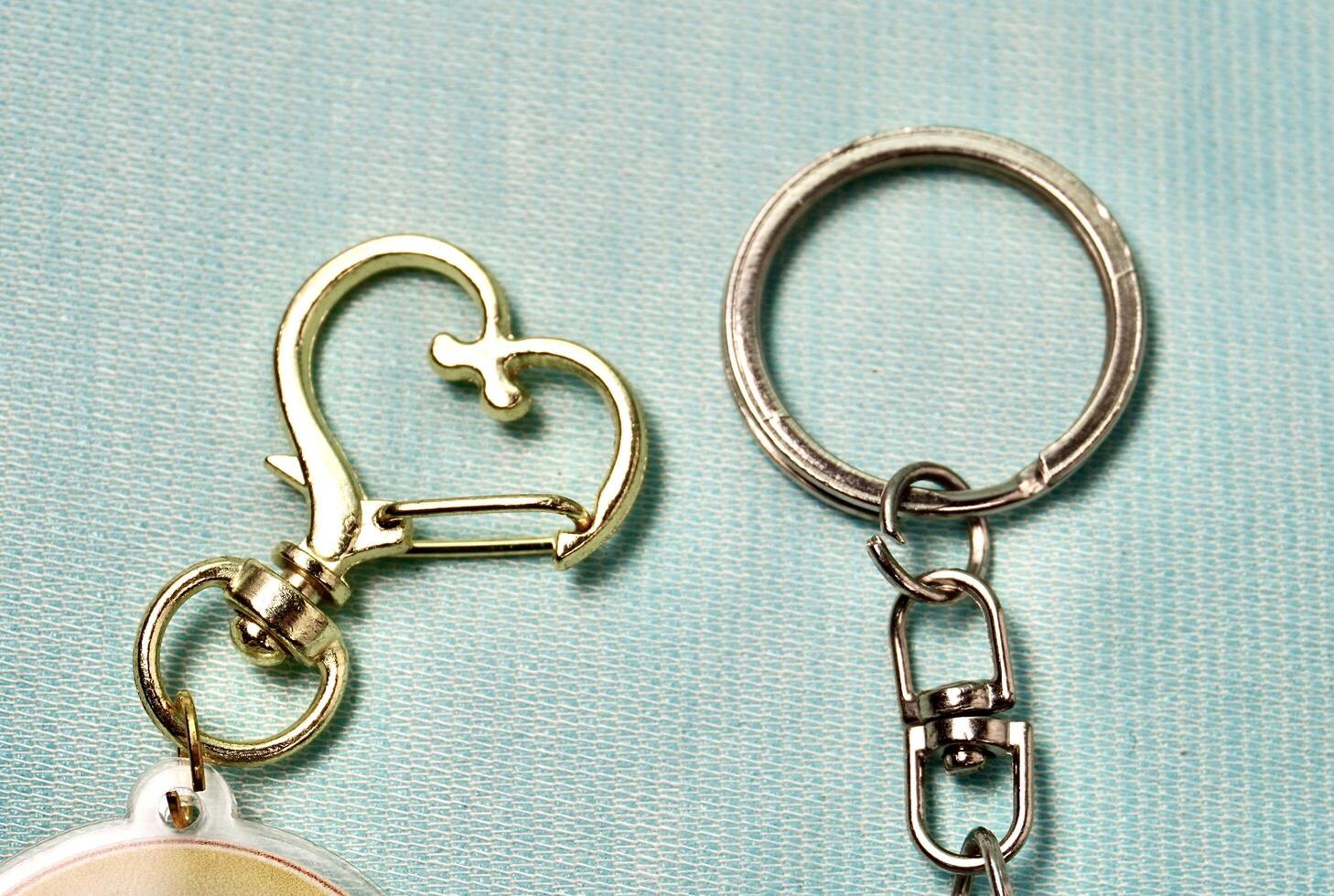Key chain heart and round metal ring hook clip isolated on horizontal light blue background. photo