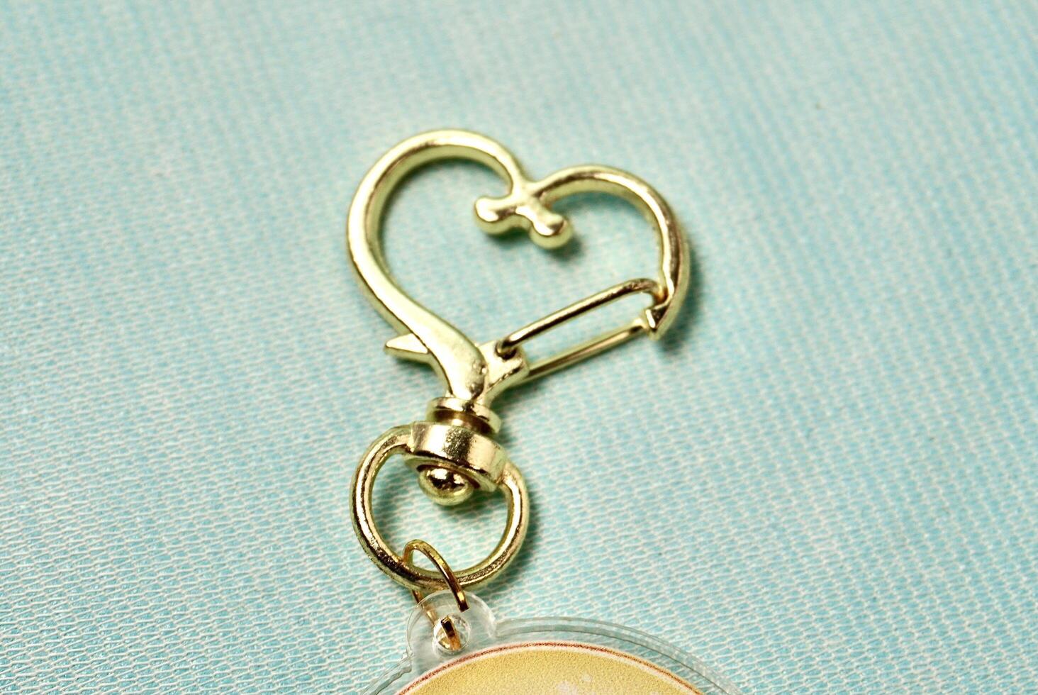 Key chain heart shaped metal ring hook clip isolated on horizontal light blue background. photo