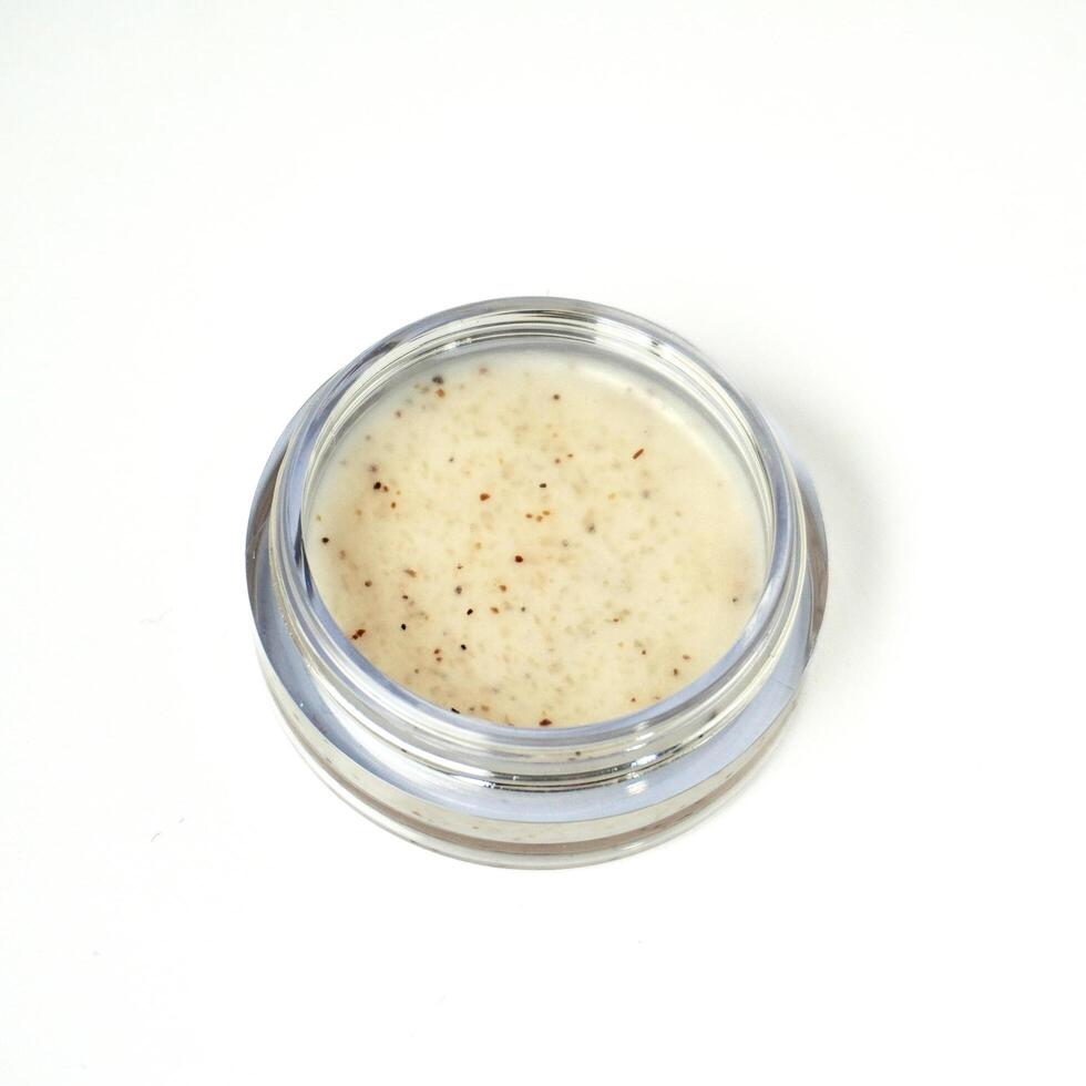 Opened lip scrub in small glass container isolated on square white background. photo