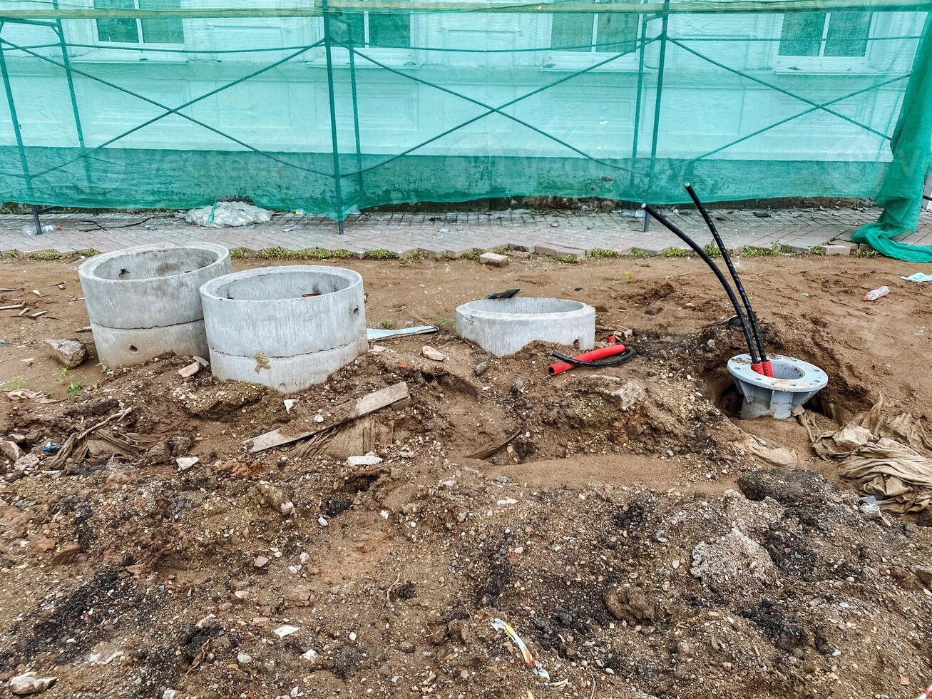 There is a sizable pile of dirt along with concrete pipes accumulated on a busy construction site, indicating ongoing work and development in the area, as teams move materials and equipment photo