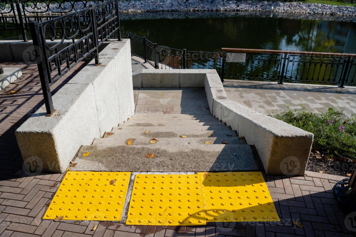 An accessible outdoor stairway features tactile yellow strips for safety and is set against a beautiful, scenic background enhancing its appeal photo