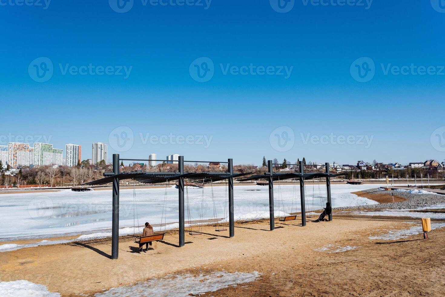 a person is sitting on a bench in a park near a frozen lake photo