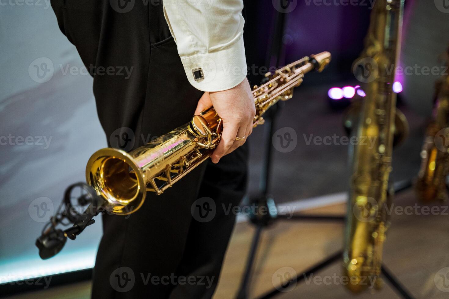 Musician in suit trousers holding brass wind instrument at concert photo