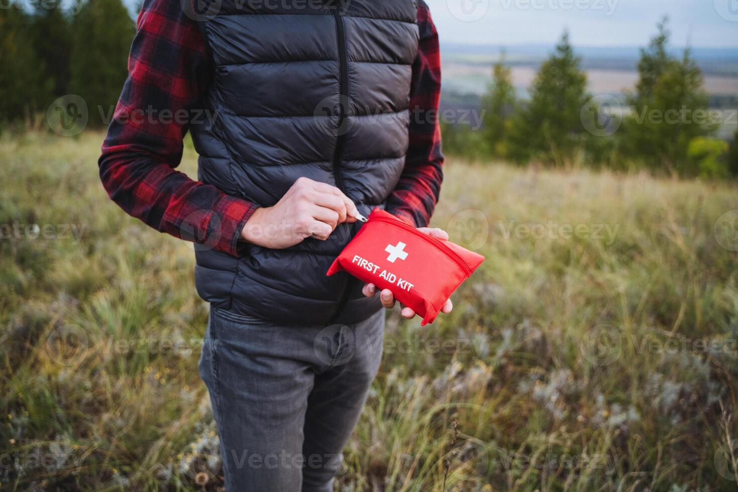 In a tranquil open field, a man holds a first aid kit, ready to help anyone in need. The calming surroundings offer a safe space for those seeking comfort in tough times photo