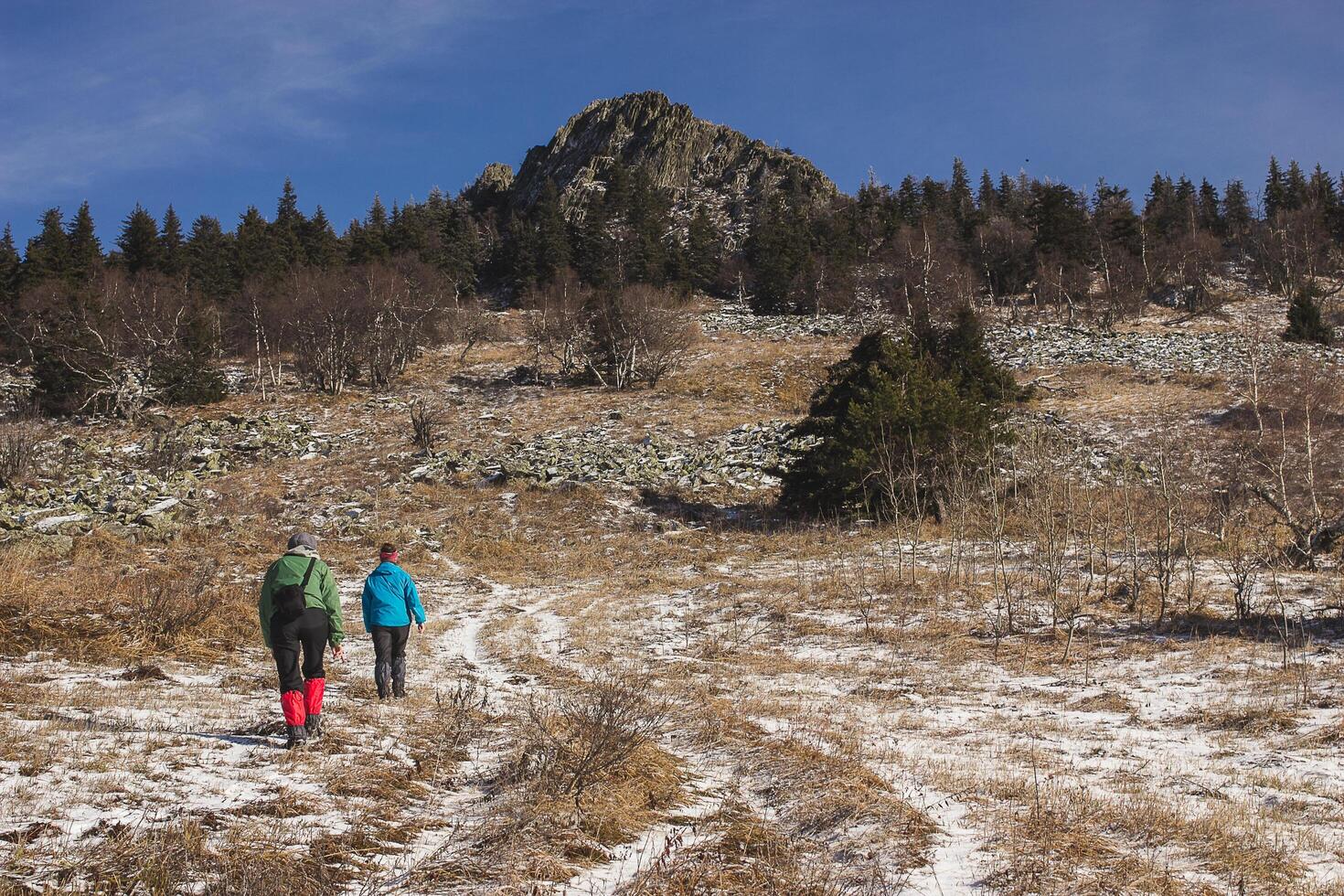 Two people walking in a snowy mountain landscape under a cloudy sky photo