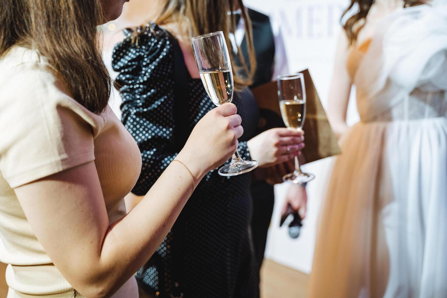 Women at event in formal wear holding champagne glasses photo