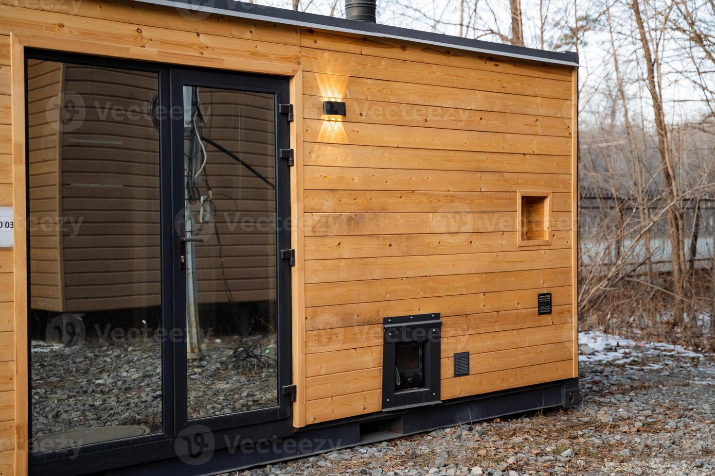 This charming wooden house, featuring a large glass door, warmly invites natural light to flow inside, offering a serene beauty for those who truly appreciate the wonders of nature photo