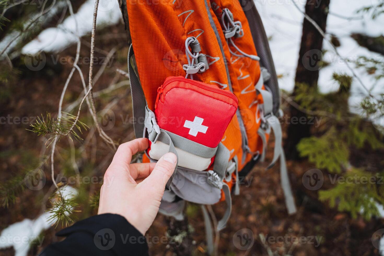 A red first aid kit with a white cross is in the pocket of the backpack, equipment for traveling alone, trekking in the mountains, bushcraft. photo