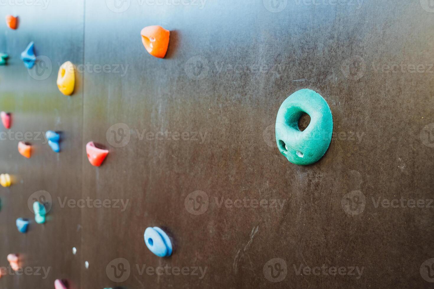 This detailed closeup shot of a climbing wall prominently features a circular hole located at its center, beautifully showcasing the walls unique design, texture, and craftsmanship photo