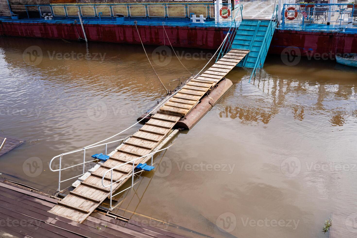 A sturdy wooden bridge constructed over a flooded river, designed to allow safe passage and connections despite the flowing water, showcasing impressive engineering and material use photo