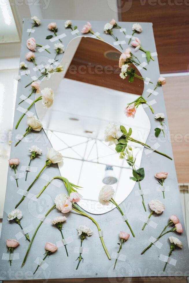 A table with a rectangular mirror surrounded by flowers and twigs photo