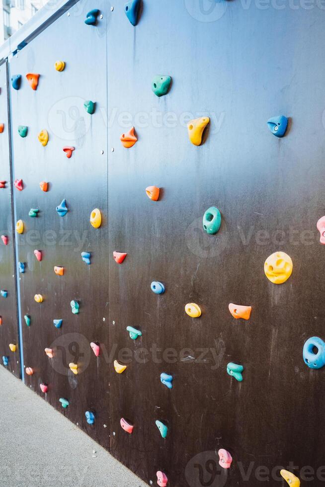 A vibrant climbing wall adorned with an array of colorful rocks of various shapes and sizes, inviting climbers to challenge themselves while enjoying the spectacular scenery photo