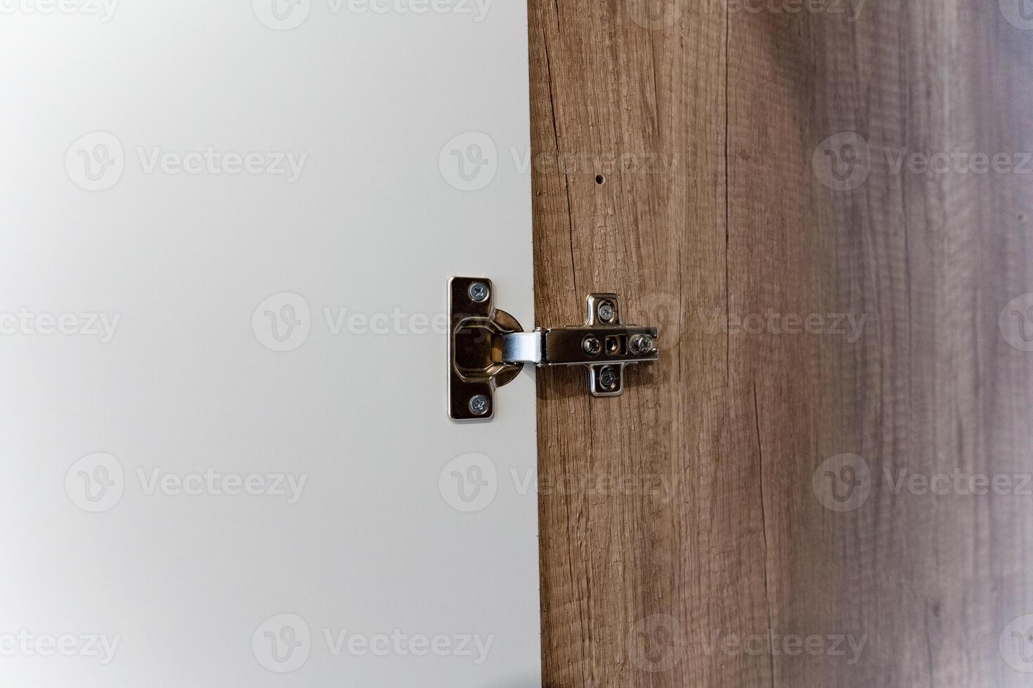 This is a detailed closeup image showcasing a door hinge that is installed on a beautifully crafted wooden door, emphasizing the intricate design and craftsmanship involved photo