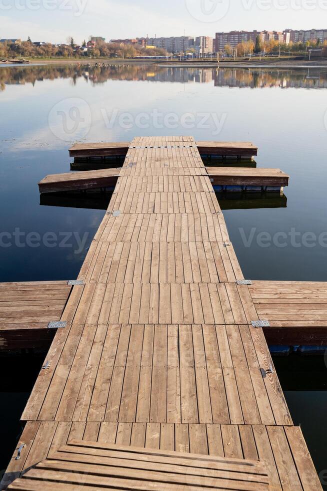 A picturesque wooden dock extends gracefully into a serene lake, while a vibrant city skyline stands majestically in the background, creating a beautiful contrast of nature and urban life photo