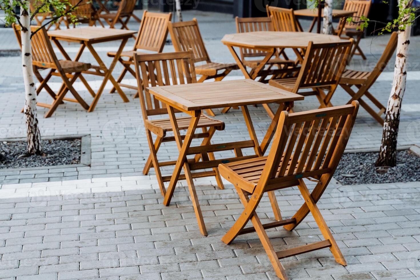 Outdoor furniture set with wooden folding tables and chairs on a brick sidewalk photo