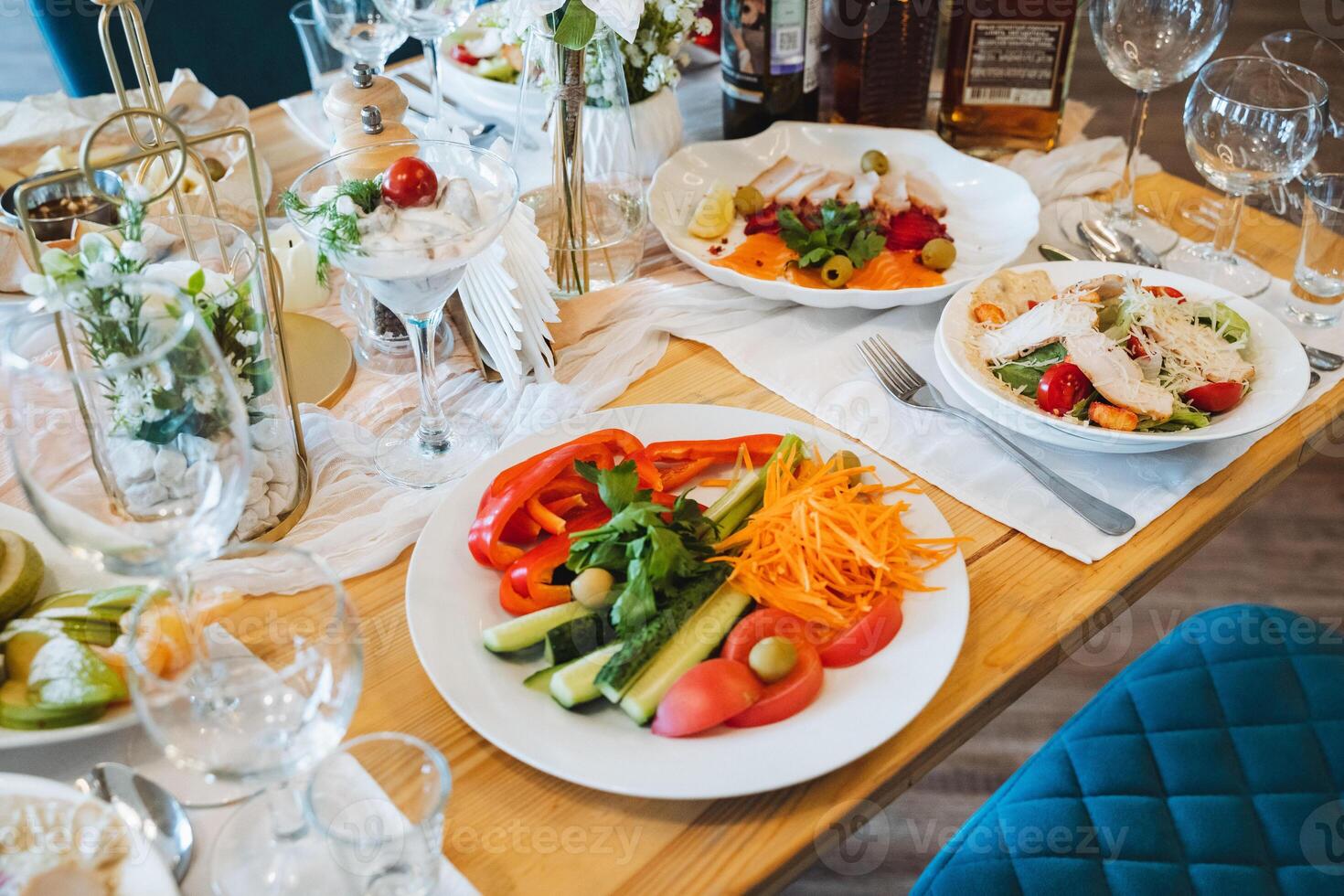 A beautifully crafted wooden table adorned with various plates of delicious food and elegant wine glasses, creating an inviting atmosphere for sharing and enjoying a meal together photo