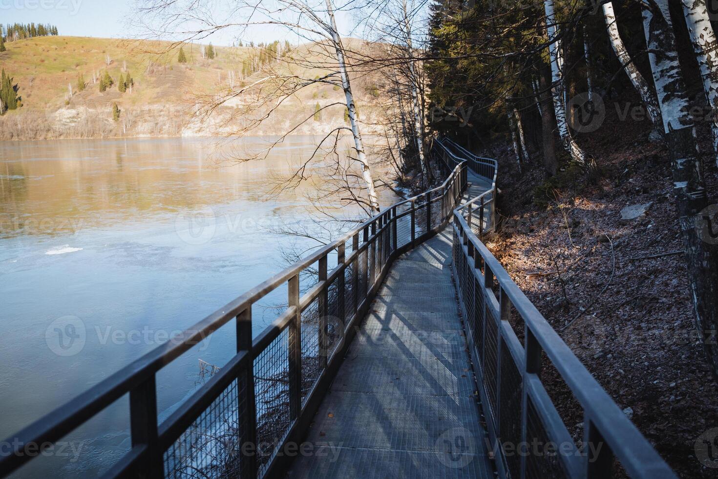Metal bridge with railing in the national park, walking path along the pond, autumn in the mountains, iron bridge, place for outdoor recreation. photo