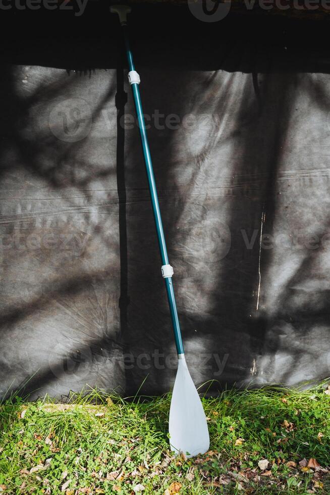 A paddle is currently resting on the lush green grass that is situated in front of a tent, creating a serene outdoor scene that captures the essence of nature and camping photo