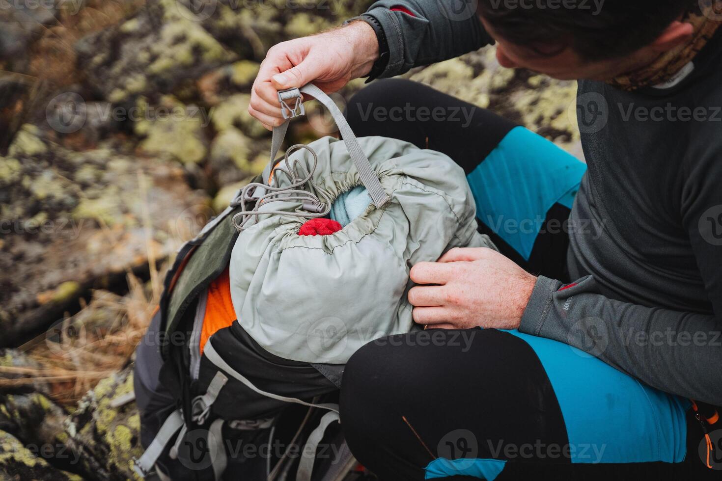 Man on rock packing backpack with soil and grass background photo