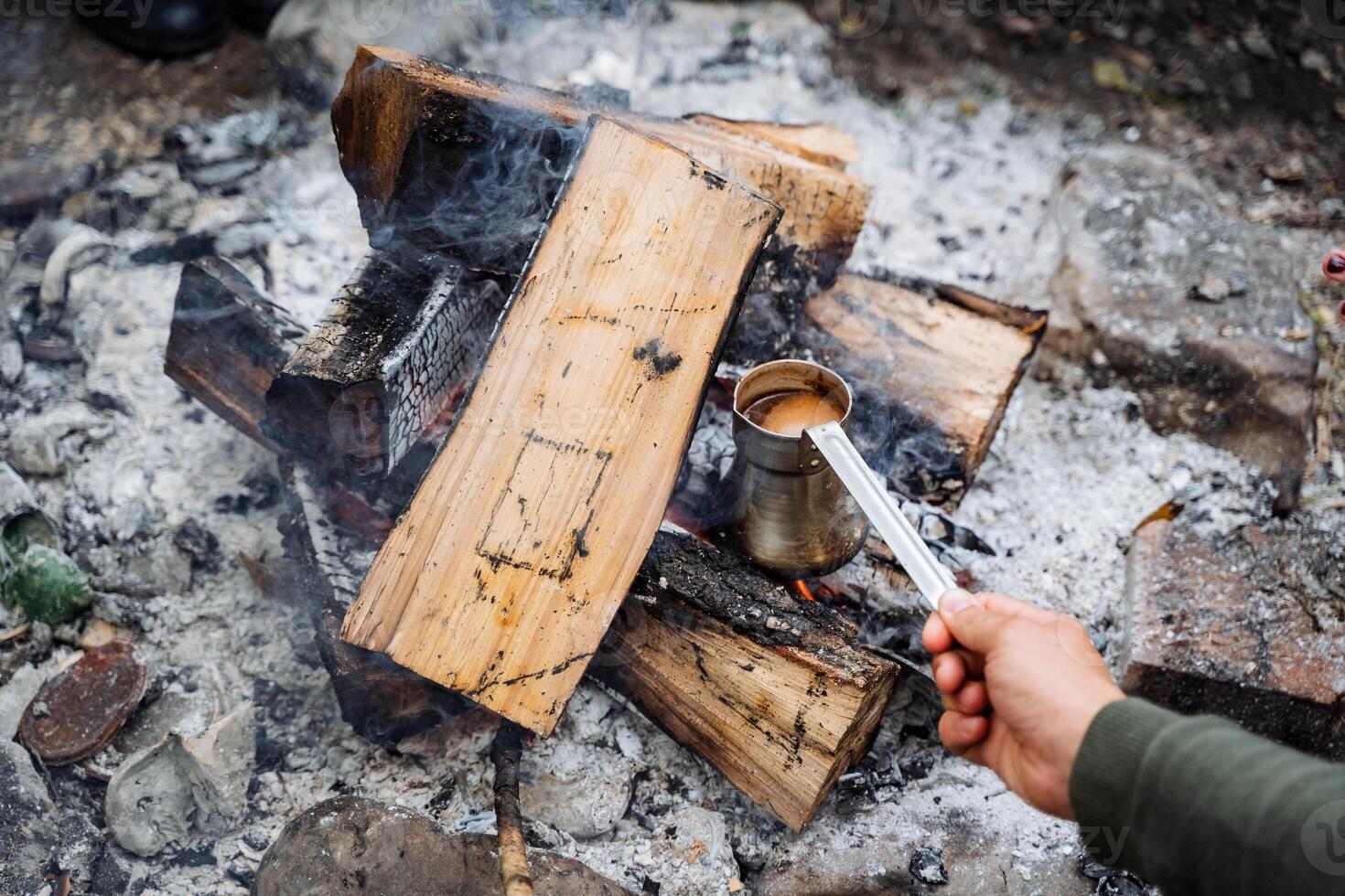 Experience the serenity of the great outdoors as you savor a freshly brewed cup of coffee by a campfire, basking in natures tranquility and the warmth of the flames photo