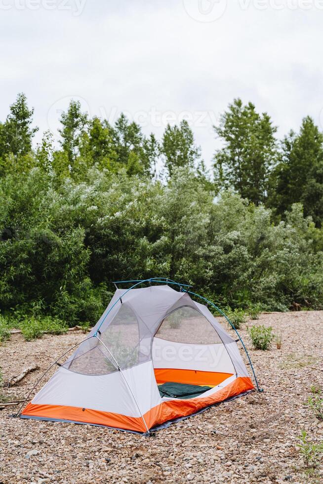 In the forest, a tent is set up, harmonizing with the trees, grass, and the clear sky. This natural environment provides a serene backdrop for camping and immersing in nature photo