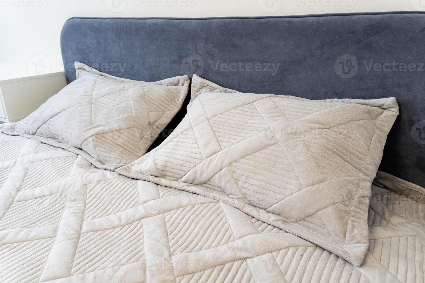 Experience the ultimate in comfort and relaxation with an elegant bed setting, featuring soft textured pillows and a beautifully quilted coverlet in a modern bedroom photo