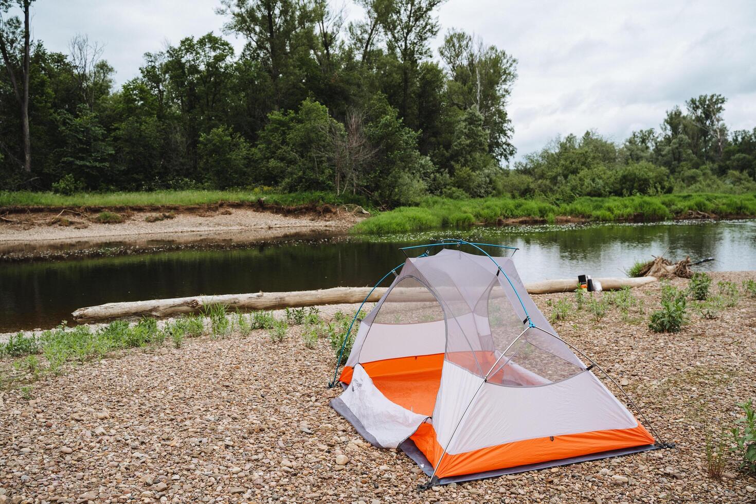 Experience a peaceful camping trip by the river with tent stay and beautiful nature views. Ideal for relaxation and outdoor adventures in a tranquil forest setting photo