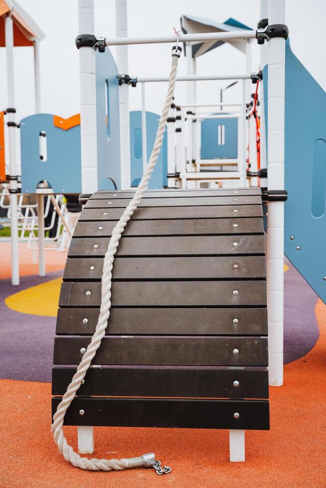 A sturdy rope is hanging down from a wooden structure that is part of the playground, providing children an exciting play element to enjoy while they are having fun outdoors photo