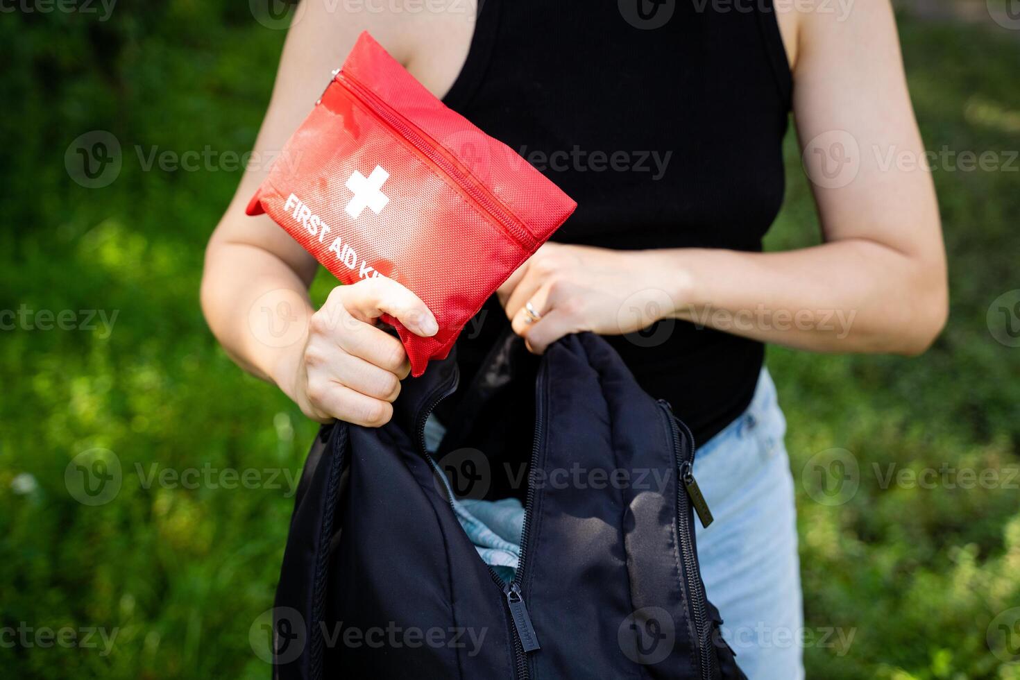A woman is meticulously placing a first aid kit into her backpack, making sure it fits snugly and securely for her highly anticipated and thrilling upcoming outdoor adventure photo