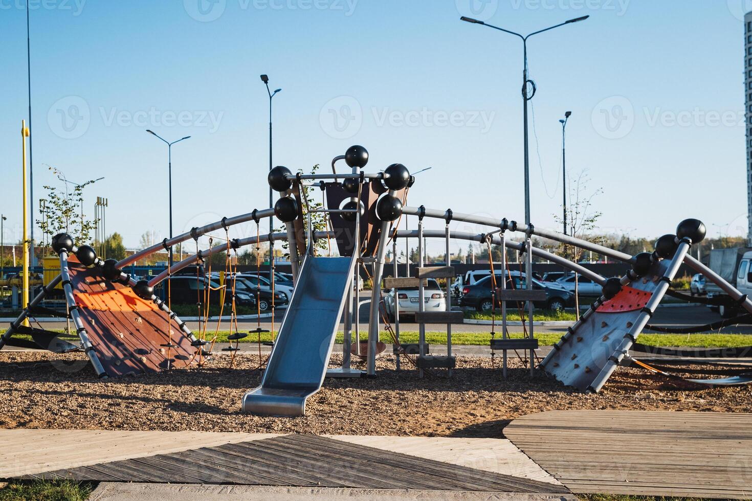 In a parking lot, there is a vibrant playground that features a tall slide alongside a challenging climbing wall, providing fun and recreational opportunities for children and families photo