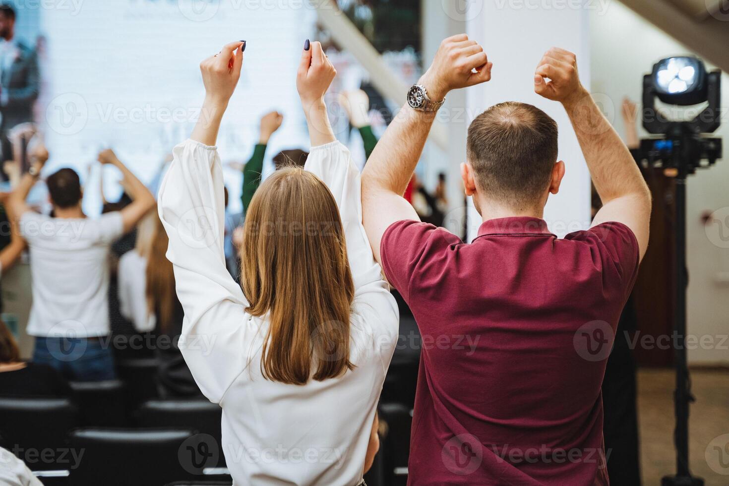 A group of people are joyfully gesturing with raised hands at a leisure event photo
