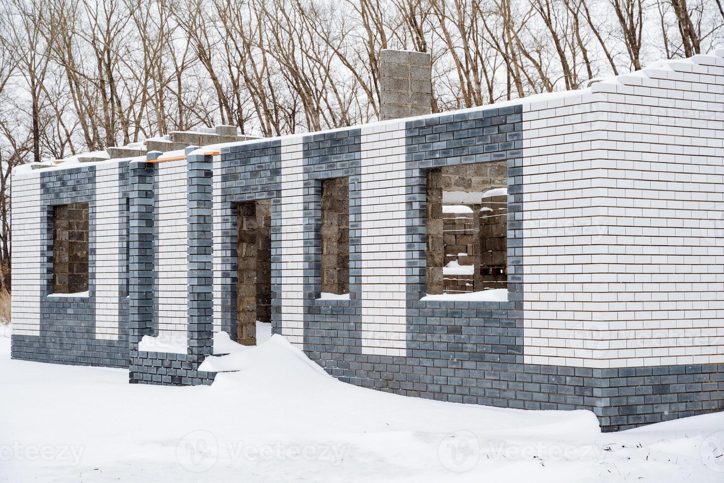 A large brick building, featuring many windows, is presently covered by a thick layer of glistening snow, crafting a stunning winter scene amidst the frigid temperatures of the cold season photo