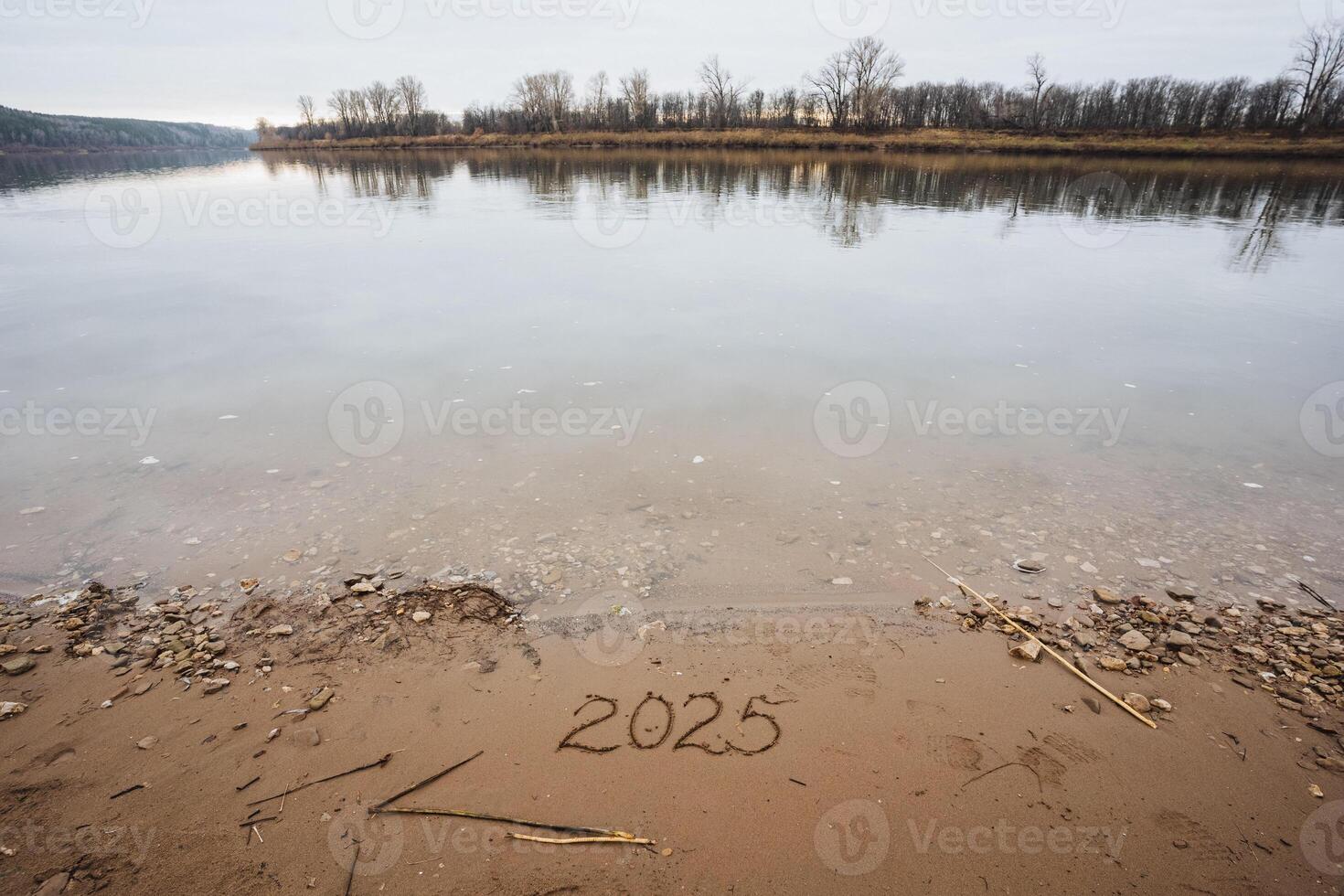 As the year 2025 is elegantly inscribed in the soft, warm sand on the beautiful beach, gentle waves gracefully meet the shore, creating a peaceful and tranquil scene beneath the vast sky photo