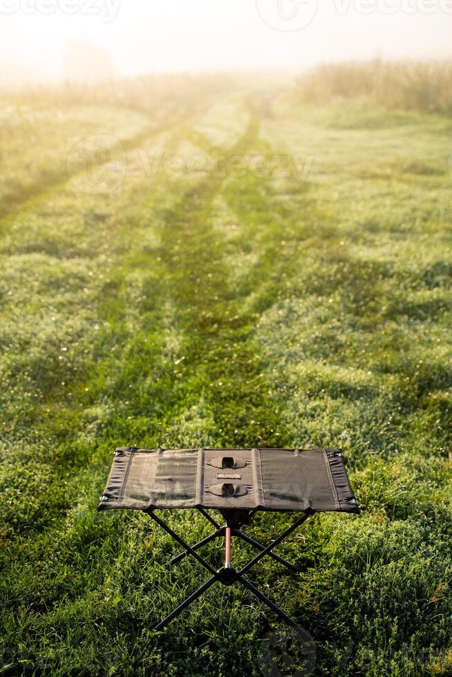 In the center of a vast and open grassy field, there exists a small table that has been placed there, surrounded by the beauty of nature and the vibrant green grass all around it photo