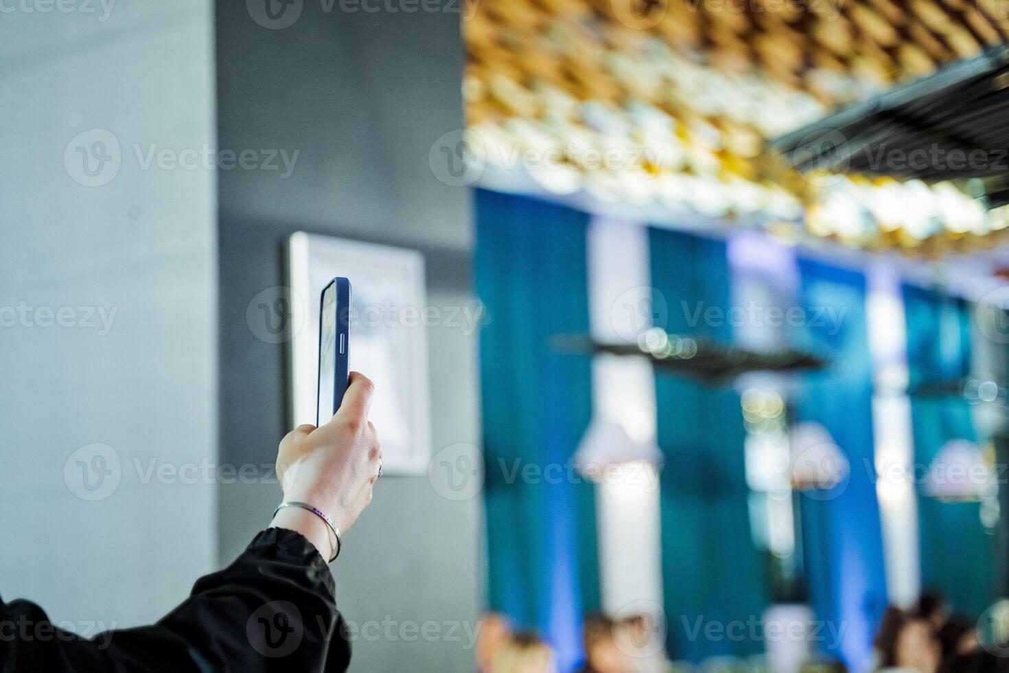 Person at event gestures to phone, captures electric blue drone in frame photo