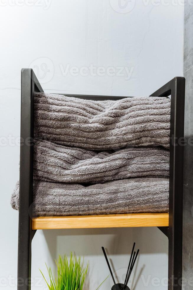 A neatly arranged stack of freshly cleaned and folded towels, perfectly placed, rests on a sturdy wooden shelf, contributing a delightful touch of organization and style to the entire space photo