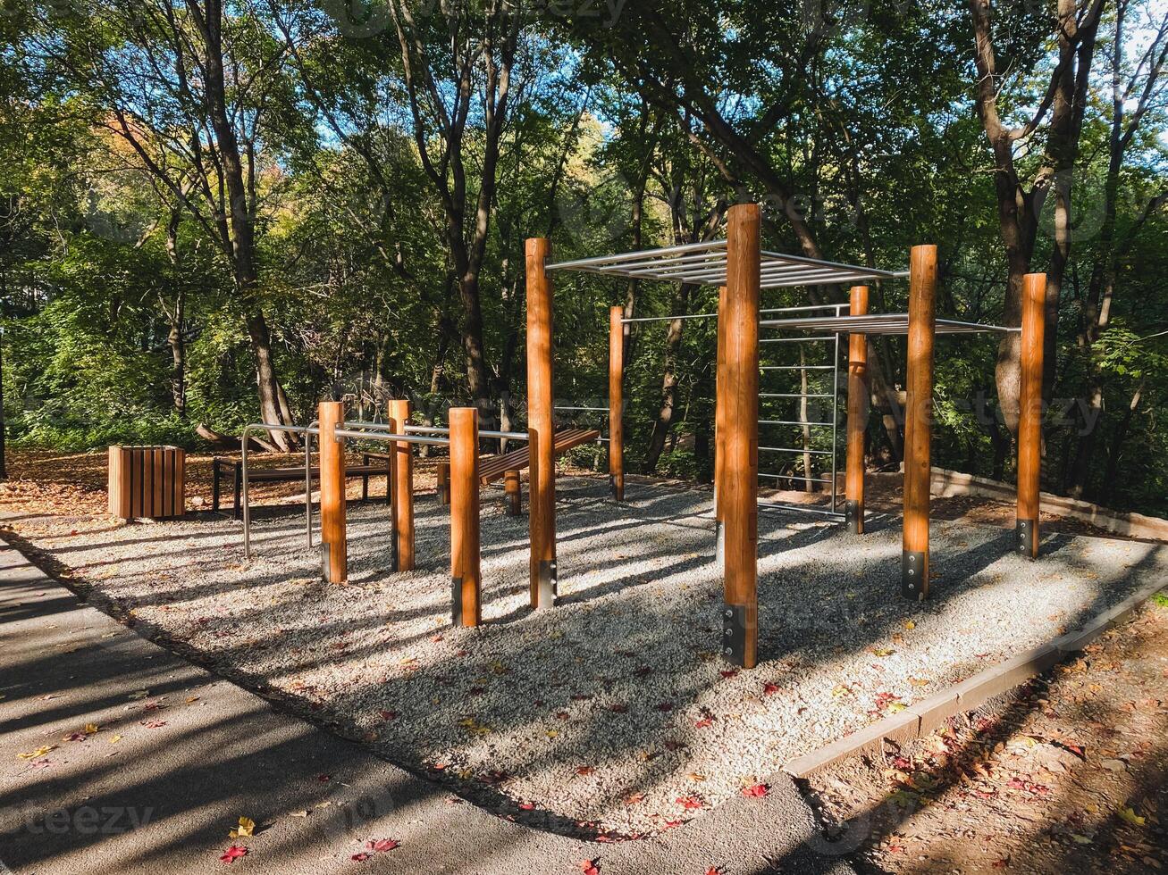 A beautifully crafted wooden playground is situated within a lush park that features trees in the background, providing a delightful natural setting for children to play and explore photo